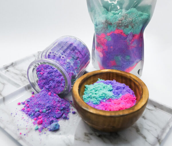 teal, purple, and pink Siren Soak bath soak in a wood bowl on tray