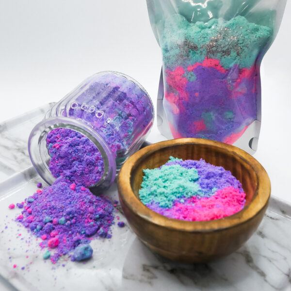 teal, purple, and pink Siren Soak bath soak in a wood bowl on tray