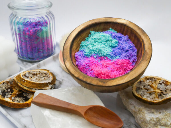 teal, purple, and pink Siren Soak bath soak in a wood bowl